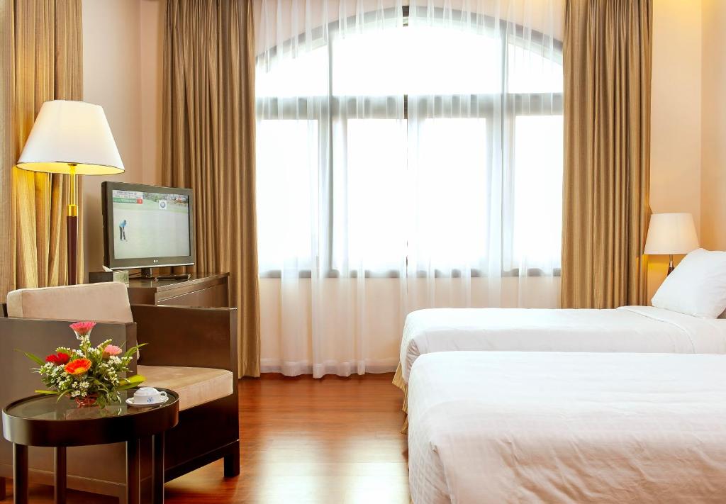 a hotel room with two beds and a television at Garco Dragon Hotel in Hanoi