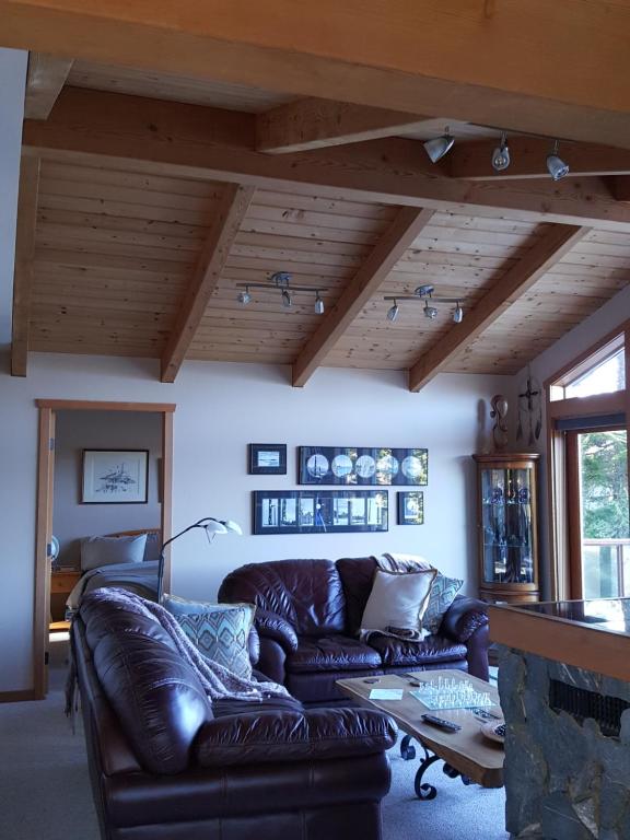 un soggiorno con divano in pelle e camino di Reef Point Oceanfront Bed and Breakfast a Ucluelet