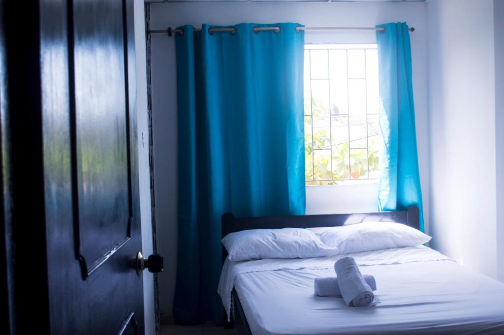 卡塔赫纳Hotel Paseo Bolivar的一间卧室，有一张带蓝色窗帘的床和一扇窗户