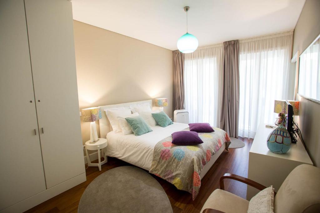 Cardosas Story Apartments by Porto City Hosts في بورتو: غرفة نوم مع سرير مع وسائد أرجوانية عليه