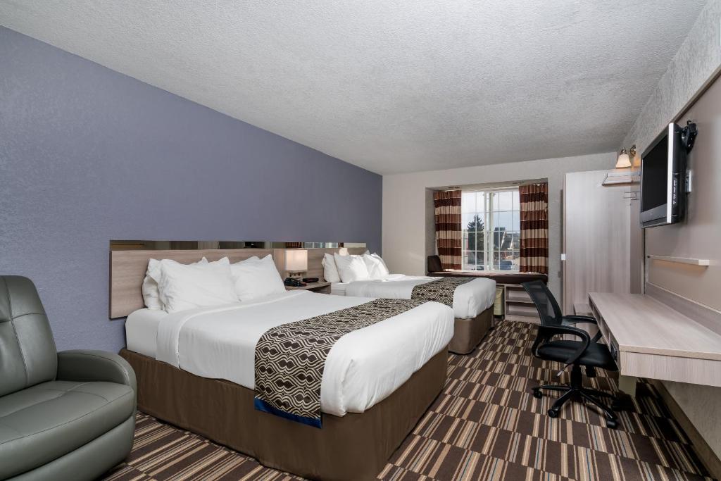 Habitación de hotel con 2 camas y escritorio en Microtel Inn & Suites by Wyndham Rochester North Mayo Clinic, en Rochester