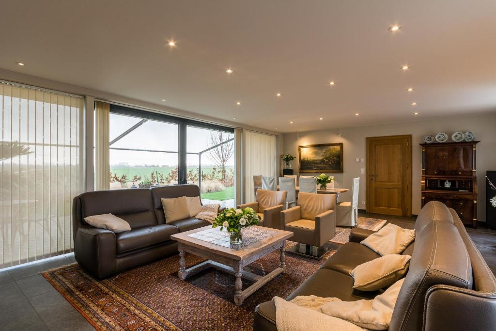 uma sala de estar com sofás e uma mesa em Polderwoning 'Cleylantshof' em Sint-Laureins