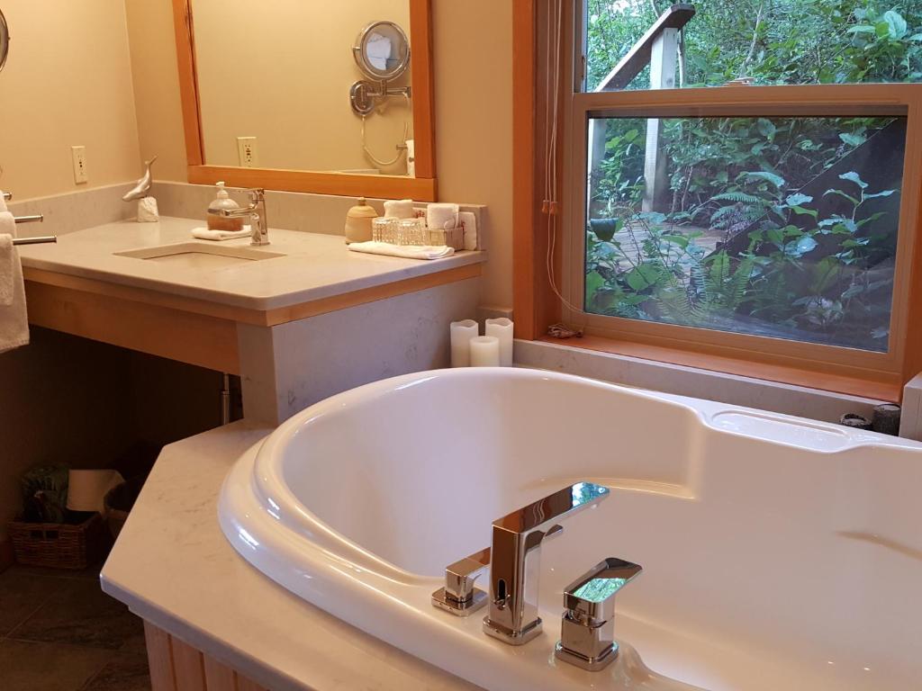 un bagno con vasca, lavandino e finestra di Reef Point Oceanfront Bed and Breakfast a Ucluelet