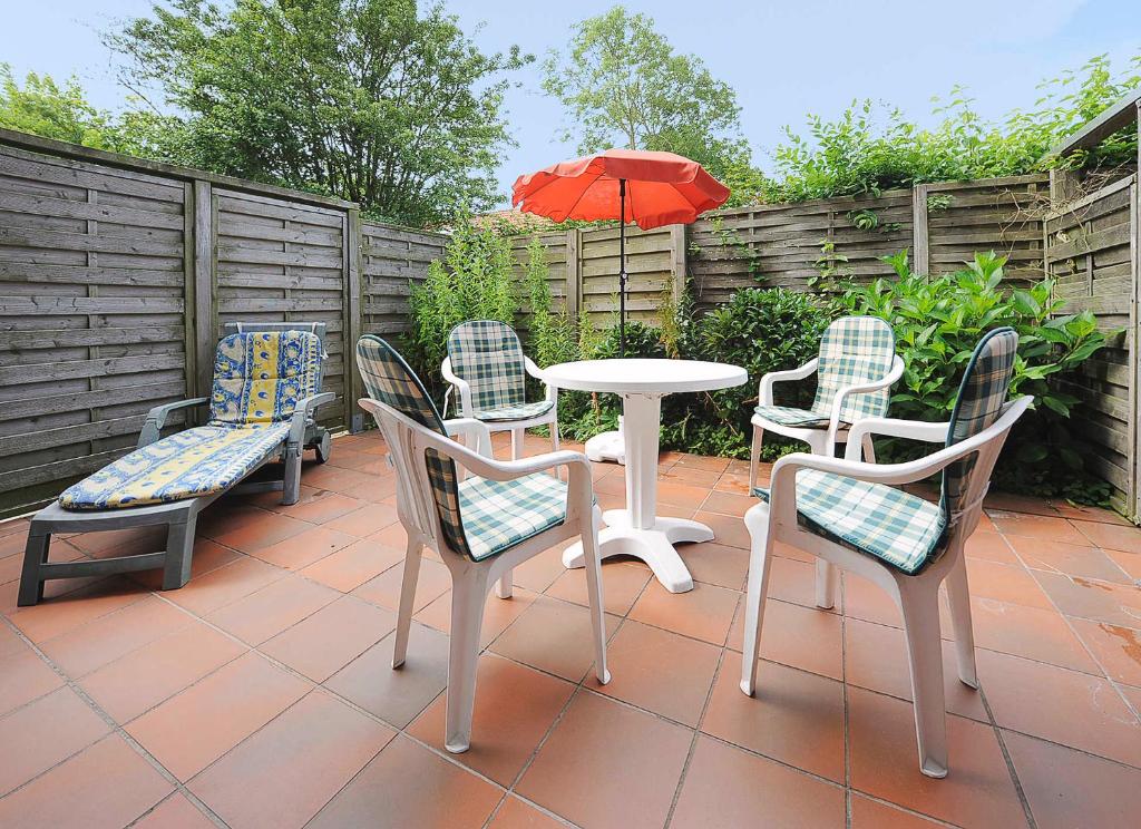 eine Terrasse mit Tisch und Stühlen und einem Sonnenschirm in der Unterkunft Ferienwohnungen Haus Taddigshus in Bensersiel