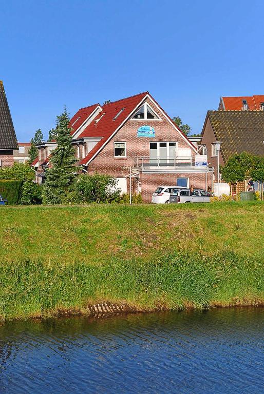 a large house next to a body of water at Ferienwohnungen Am Sieltor in Bensersiel