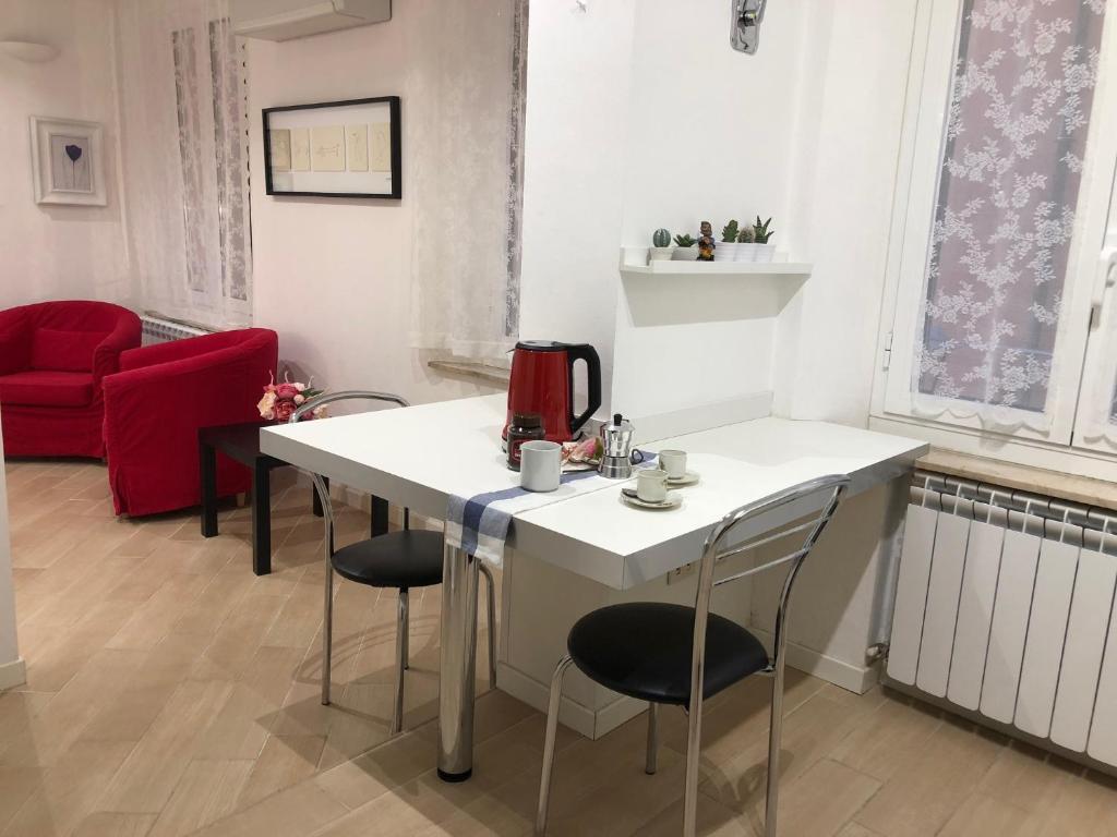 ボローニャにあるTemporary House vicolo Colombinaのテーブルと椅子、赤いソファが備わる客室です。