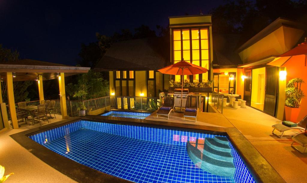 a swimming pool in front of a house at night at Butterfly Garden Villa in Laem Set Beach