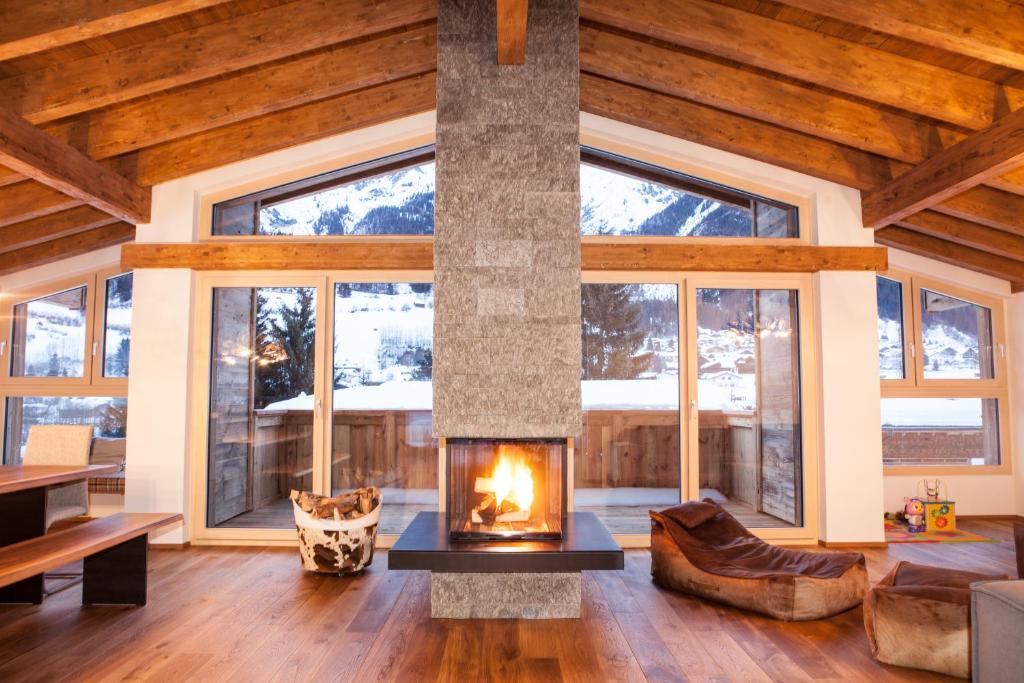 a living room with a fireplace and large windows at Riffler Lodge in Pettneu am Arlberg