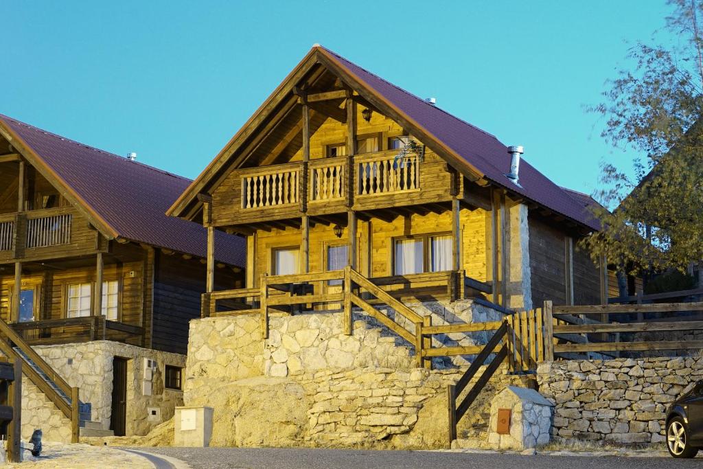 a large wooden house with a stone wall at Chalé | Penhas da Saúde - Serra da Estrela in Penhas da Saúde