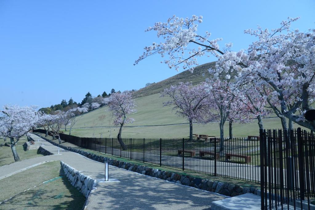 a fence with flowering trees in front of a hill at Mountain Home Lodge in Deer Park in Nara