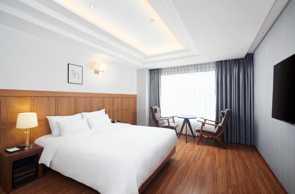 a hotel room with a large white bed and a table at Lion Hotel in Busan