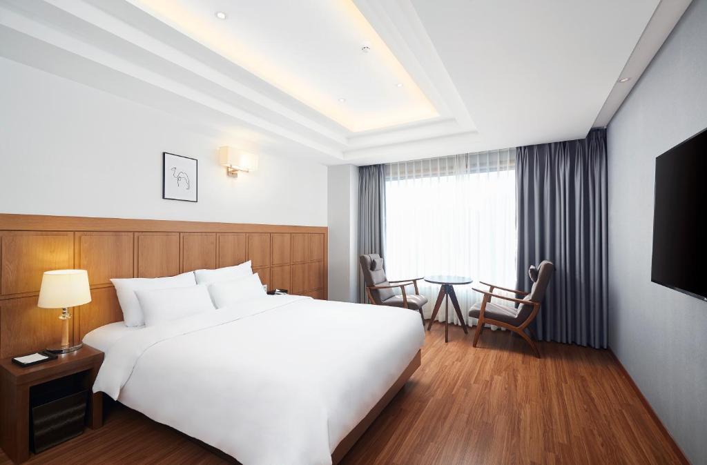 釜山にあるライオン ホテルの白い大型ベッドとテーブルが備わるホテルルームです。