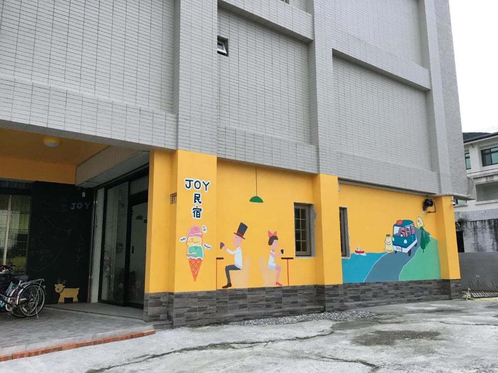 a yellow building with a painting on the side of it at JOY Homestay in Shoufeng