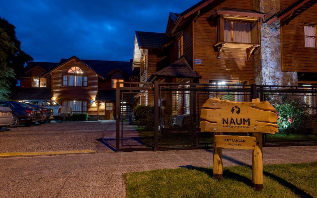 un cartel en el césped frente a una casa en Apart Hotel Naum en San Martín de los Andes