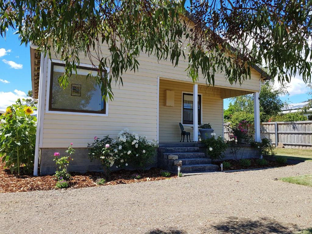 a white house with a porch with a tree at The Manager's Cottage in Grove