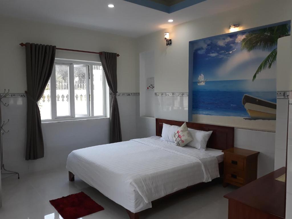 a bedroom with a white bed and a large window at Queen Motel Vung Tau in Vung Tau