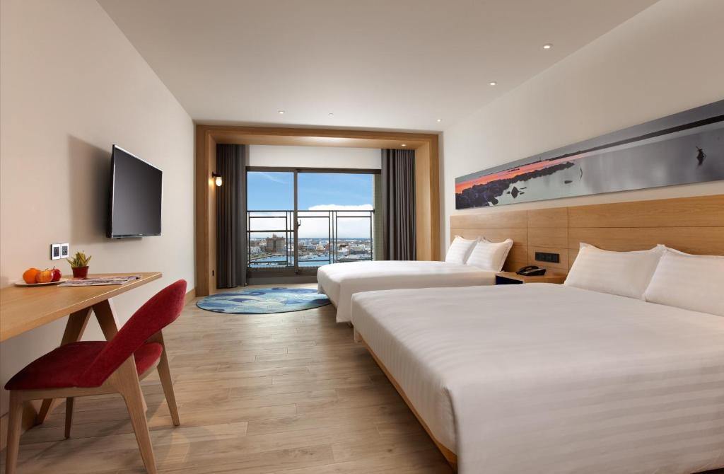 馬公市にあるディスカバリー ホテルのベッド2台とデスクが備わるホテルルームです。