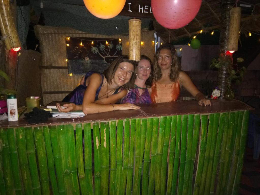 three women standing behind a green bar at a party at Gone Coastal Homestay in Varkala