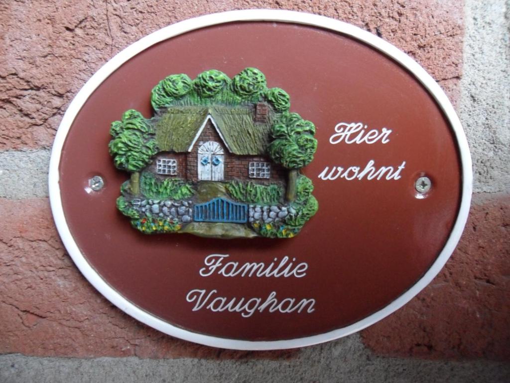 une plaque avec une maison sur le côté d'une paroi dans l'établissement Pension Heideweg, à Weeze