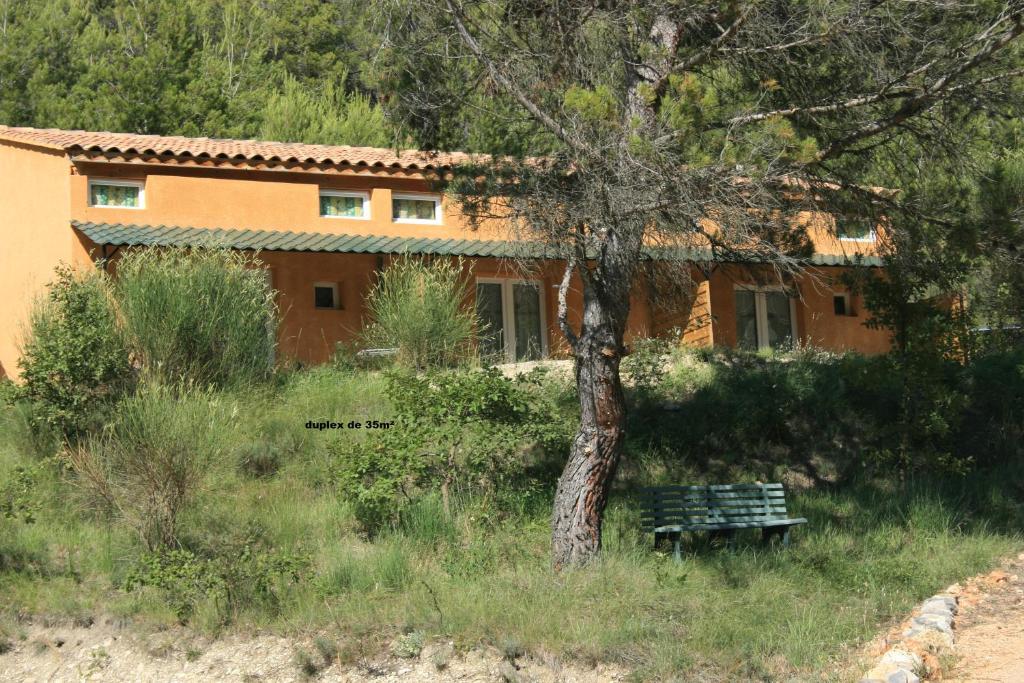 ein Haus mit einem Baum und einer Bank davor in der Unterkunft Chambre d'hôte Domaine de Bois joli in Buis-les-Baronnies