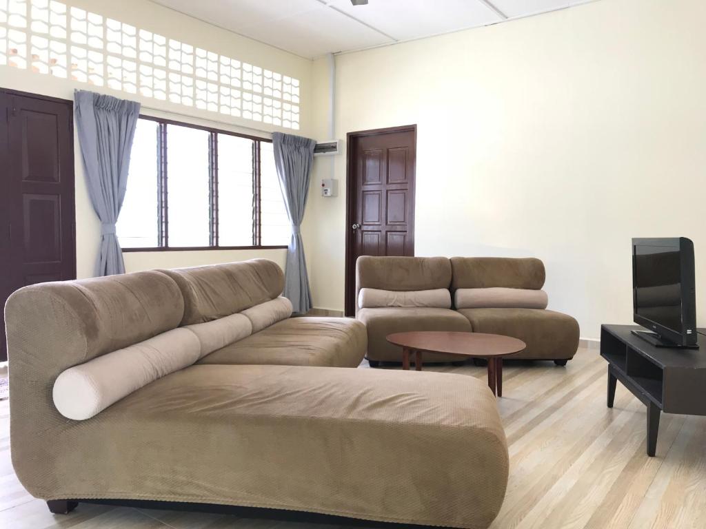 a living room with two couches and a tv at SingSport Holiday House in Mersing