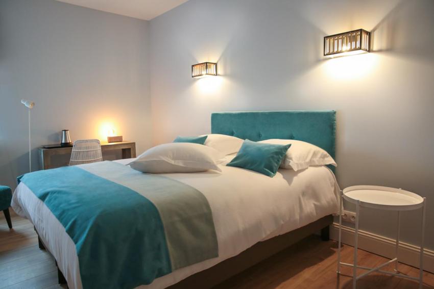 a bedroom with a large bed with blue and white sheets at Hotel Des Arts in Wimereux