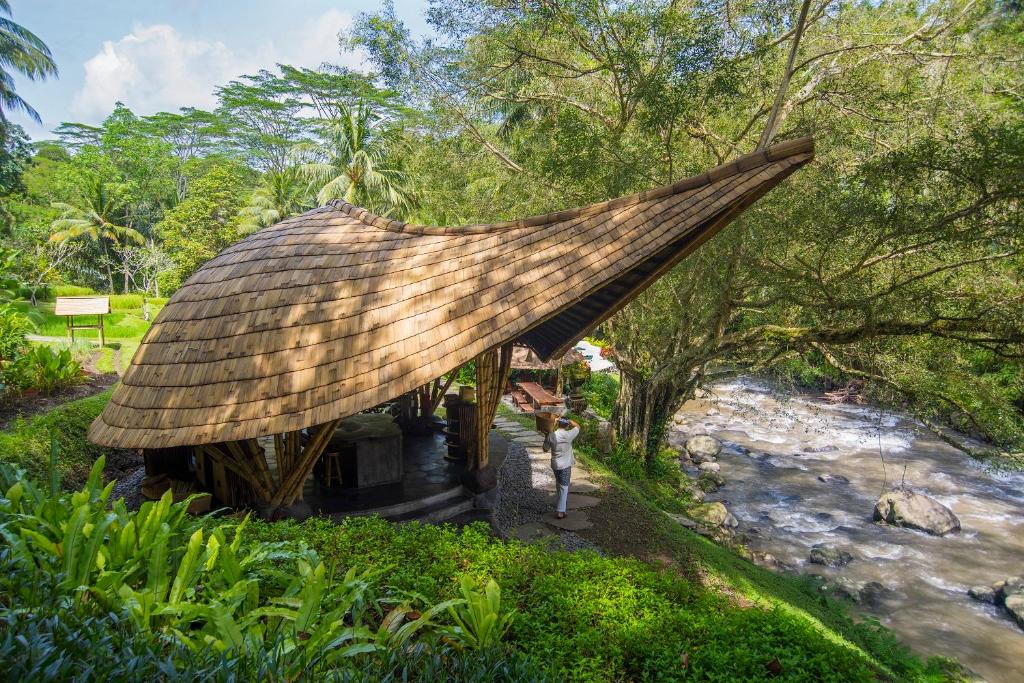 a hut with a thatched roof next to a river at Four Seasons Resort Bali at Sayan in Ubud