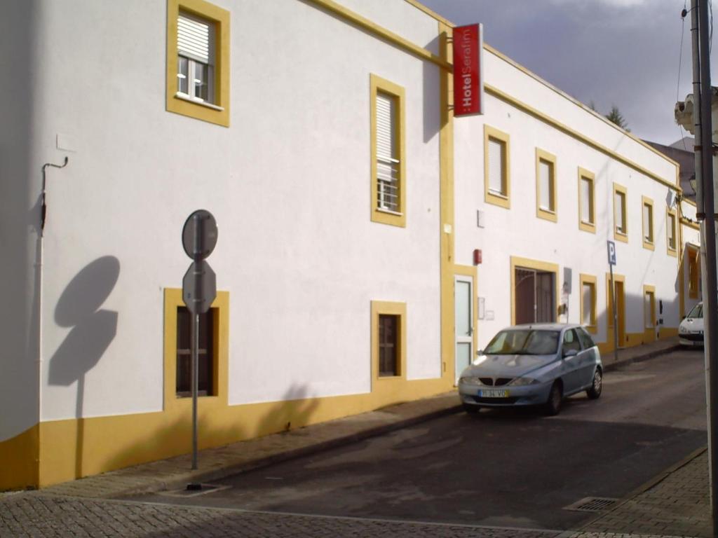 une voiture garée devant un bâtiment blanc dans l'établissement Hotel Serafim, à Almodôvar