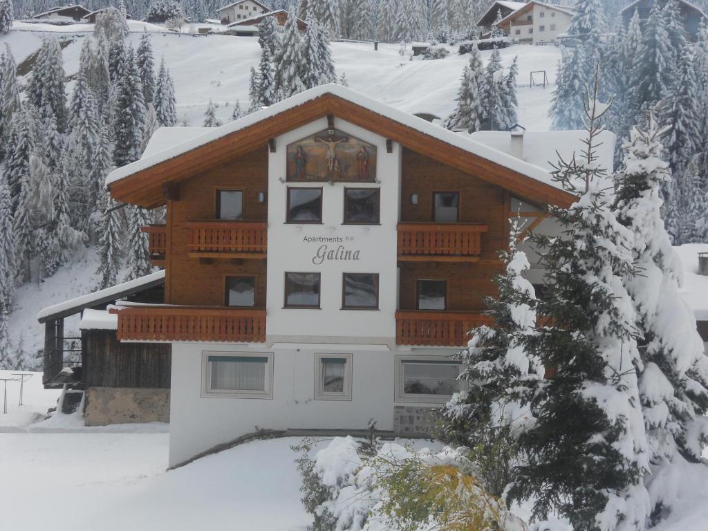 a log cabin in the snow with snow covered trees at Apartaments Galina in Selva di Val Gardena