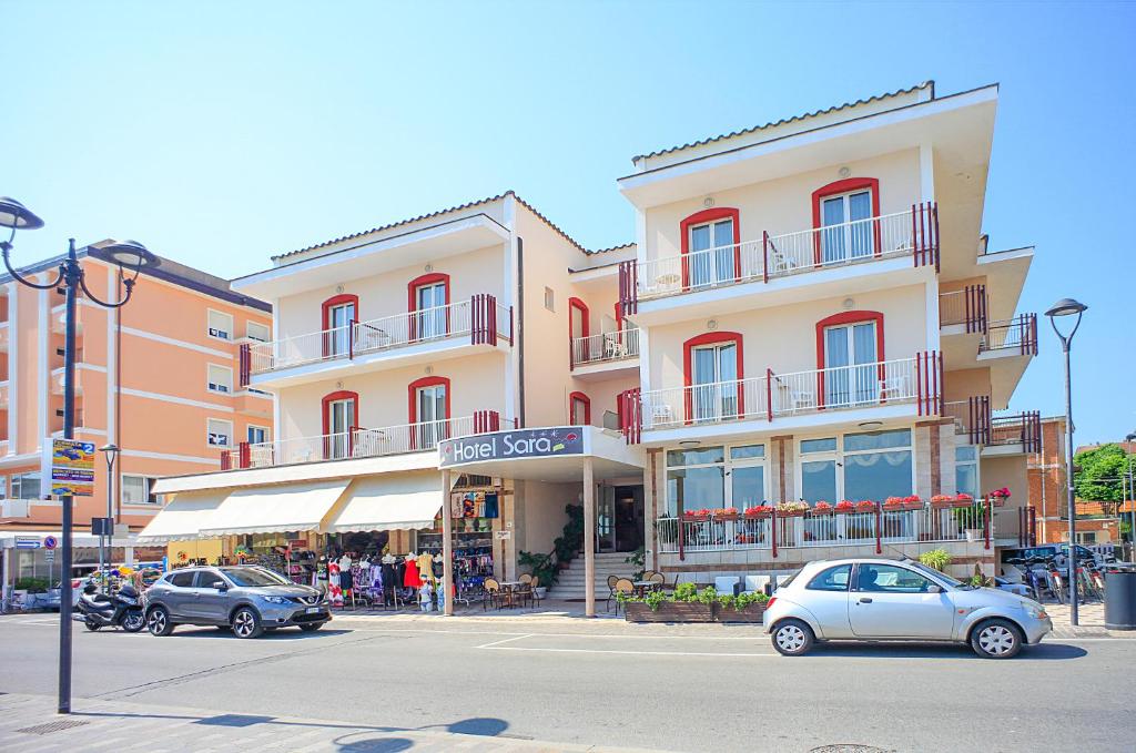 a building with cars parked in front of a street at Hotel Sara in Rimini