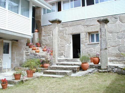 una casa in pietra con piante in vaso di fronte di Casa Rural O Pozo a Borela
