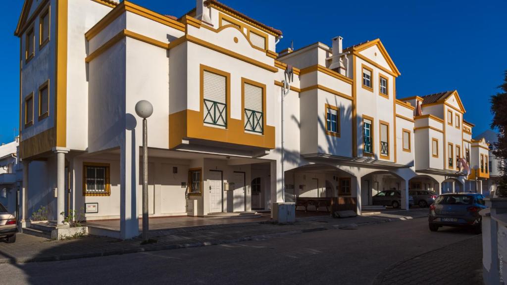 a large white building with yellow accents on a street at Family House in Baleal in Ferrel