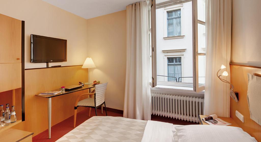a hotel room with a bed and a desk and a window at Hotel am Rathaus in Augsburg