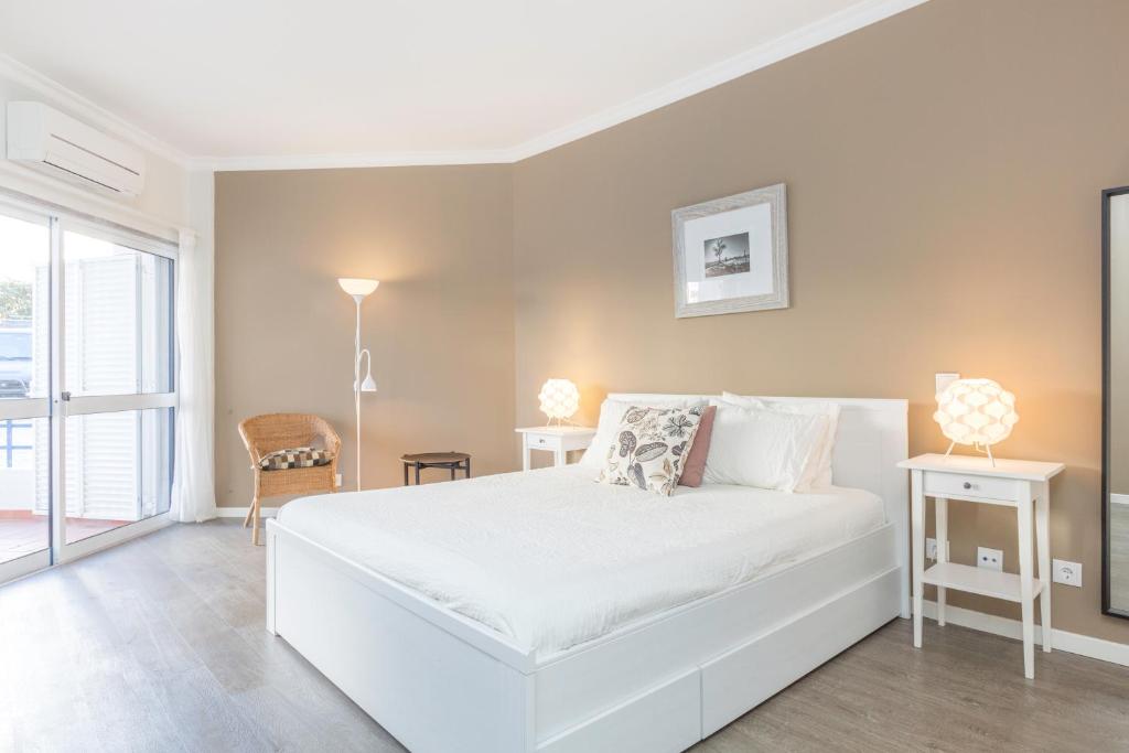 a white bedroom with a white bed and a window at ATLANTIC GARDENS 134 Condominium in Cascais