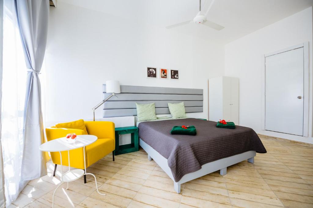 ein Schlafzimmer mit einem Bett und einem gelben Sofa in der Unterkunft Terraza Art Villa Dominicana in Punta Cana