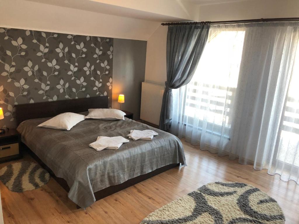 um quarto com uma cama e uma grande janela em Hotel boutique Garden Resort by Brancoveanu em Moieciu de Jos