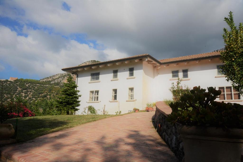 duży biały dom z ceglanym podjazdem w obiekcie B&B Macchia d'Olmo w Capaccio-Paestum