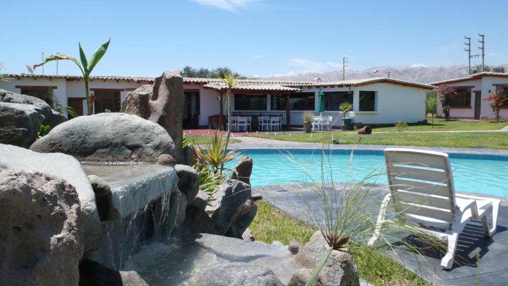 uma casa com uma piscina e uma cadeira branca em Casa Hacienda Nasca Oasis em Nazca