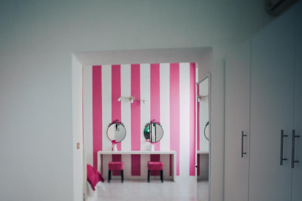 a pink and white room with a table and two mirrors at Hotel Elite in Salsomaggiore Terme