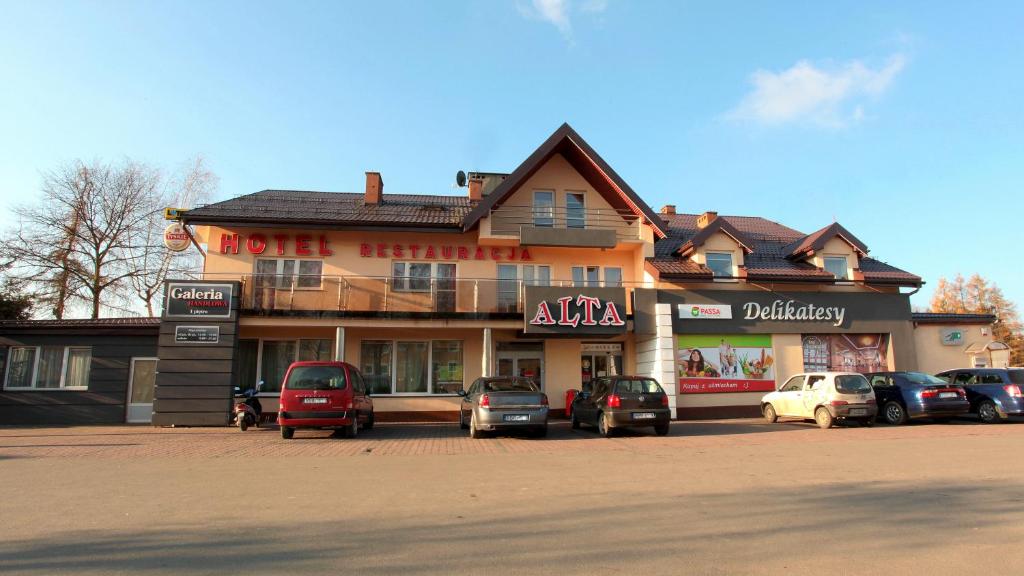 a building with cars parked in front of it at Hotel Alta in Brzozów