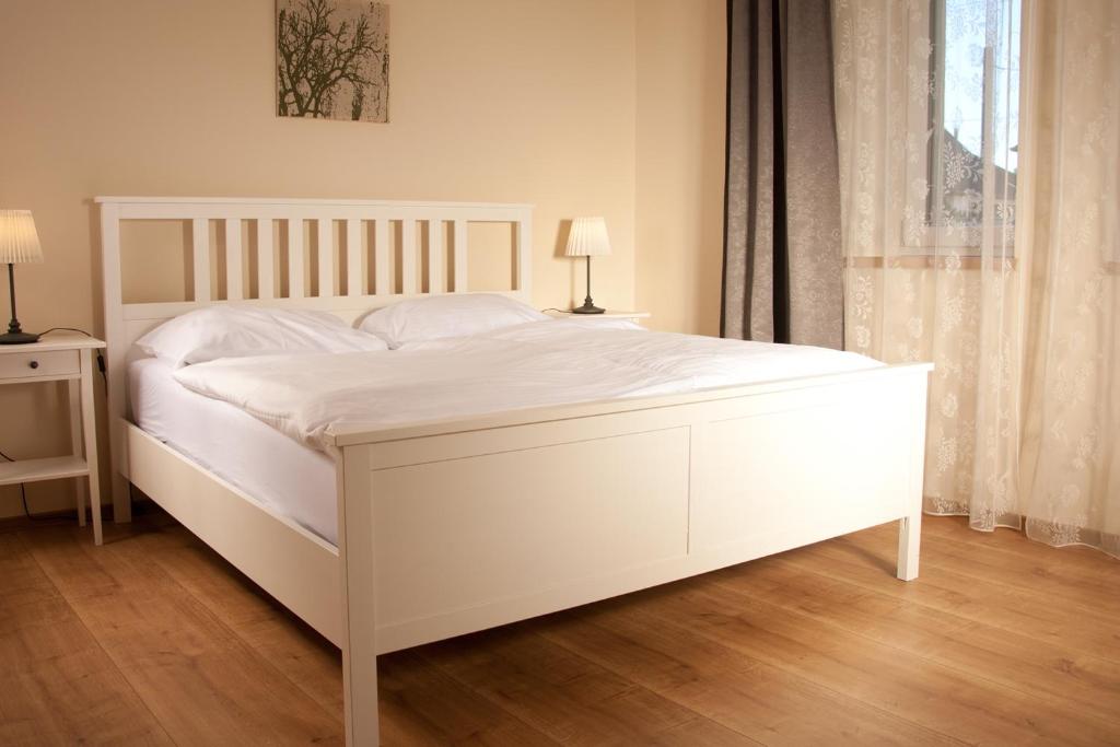 ein weißes Bett in einem Schlafzimmer mit zwei Lampen in der Unterkunft Sabines Apartments Ferienwohnungen in Frauenkirchen