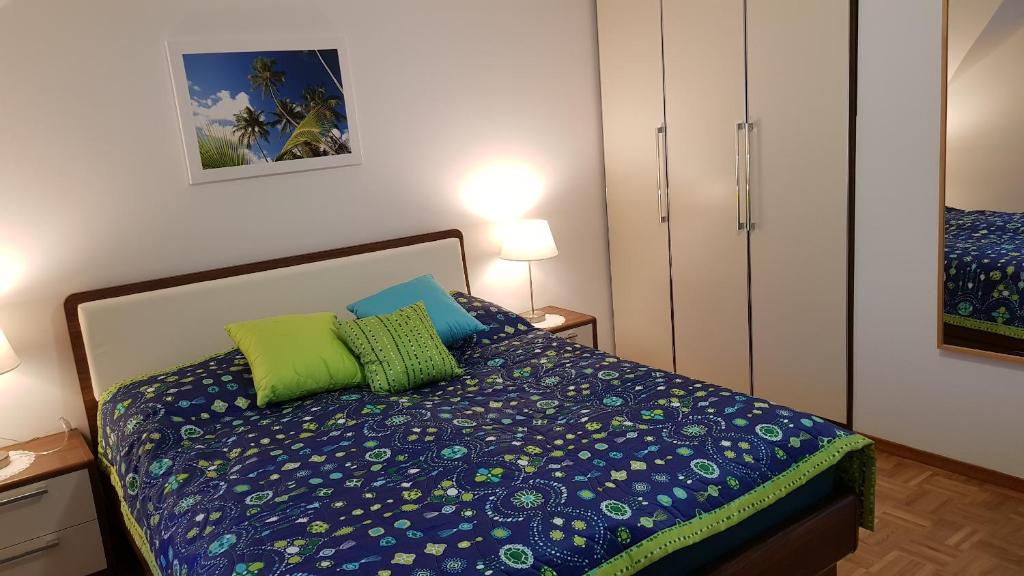 Schlafzimmer mit einem Bett mit blauer Bettwäsche und grünen Kissen in der Unterkunft Apartma Ravbar in Kranjska Gora