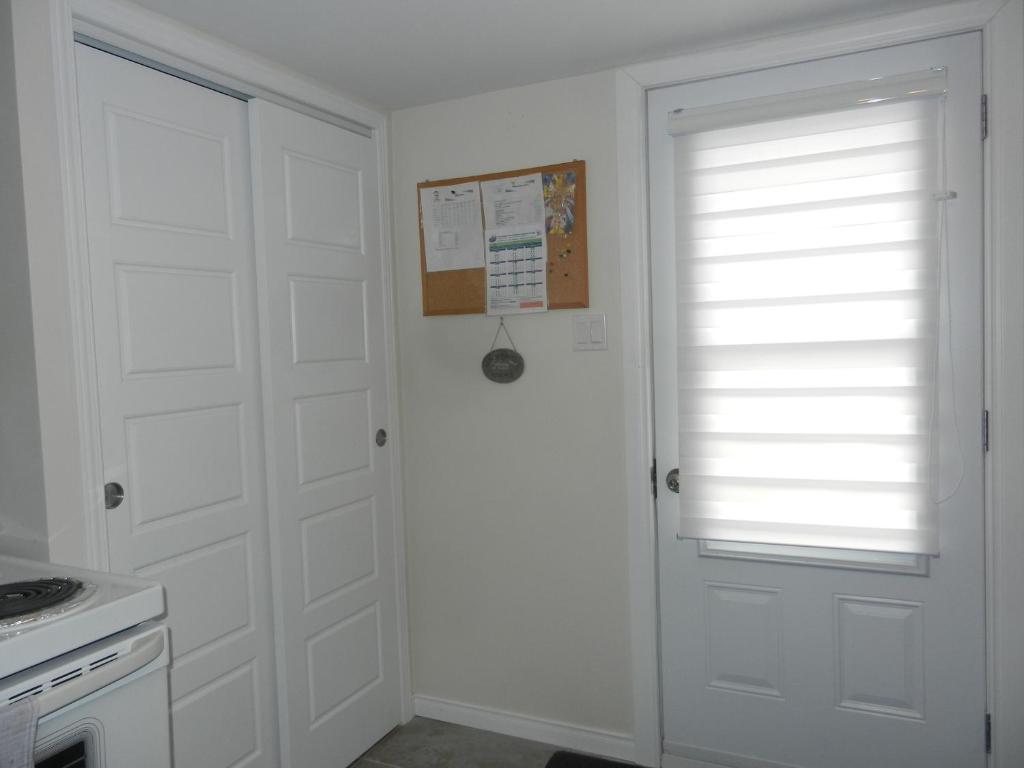 a white door in a kitchen with a window at Gite La Ptite Falaise hébergement touristique in Sainte-Anne-des-Monts