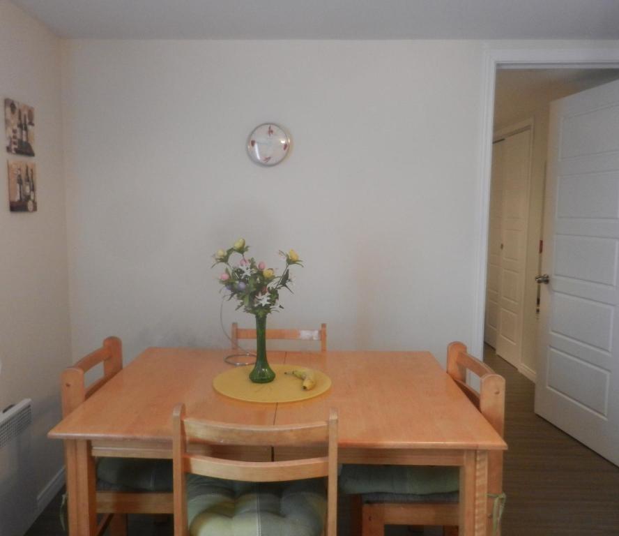 a dining room table with a vase of flowers on it at Gite La Ptite Falaise hébergement touristique in Sainte-Anne-des-Monts