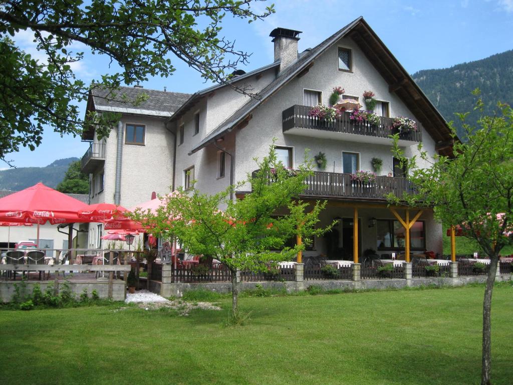 a large white building with a balcony and tables at Dormio Gasthof Höllwirt in Obertraun