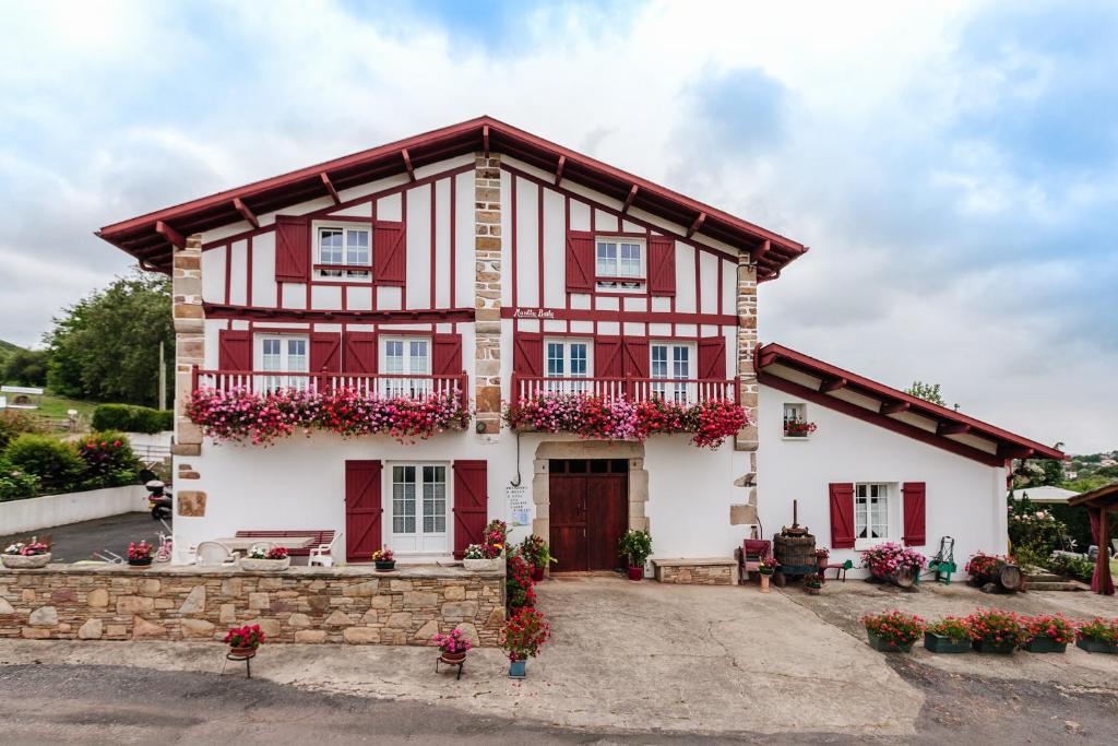 uma casa vermelha e branca com flores em Chambres d'hôtes MANTTU em Urrugne