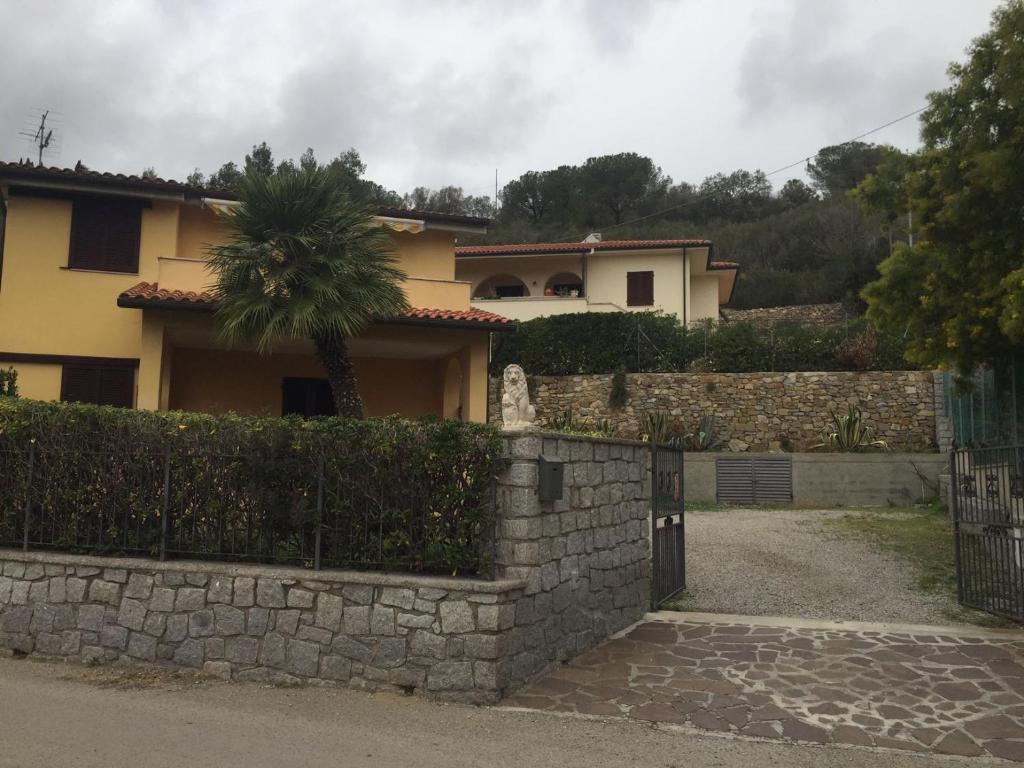 a house with a stone wall and a fence at Appartamento Fornaci in Marina di Campo