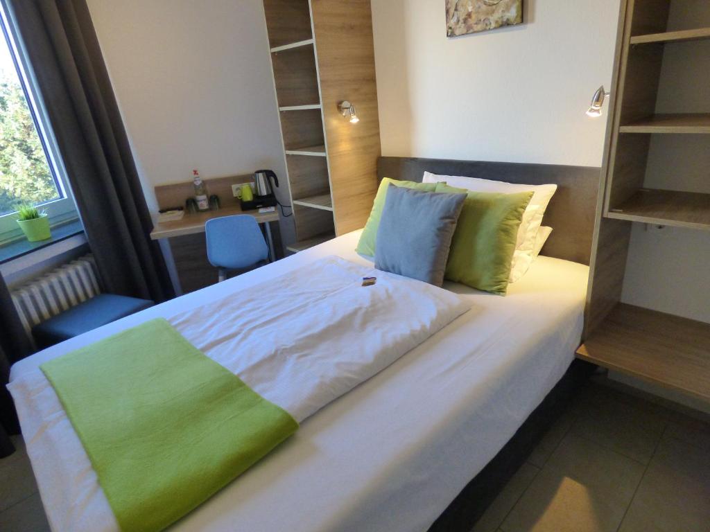 Schlafzimmer mit einem großen Bett mit grüner und weißer Bettwäsche in der Unterkunft Hotel Art Inn Dinslaken in Dinslaken