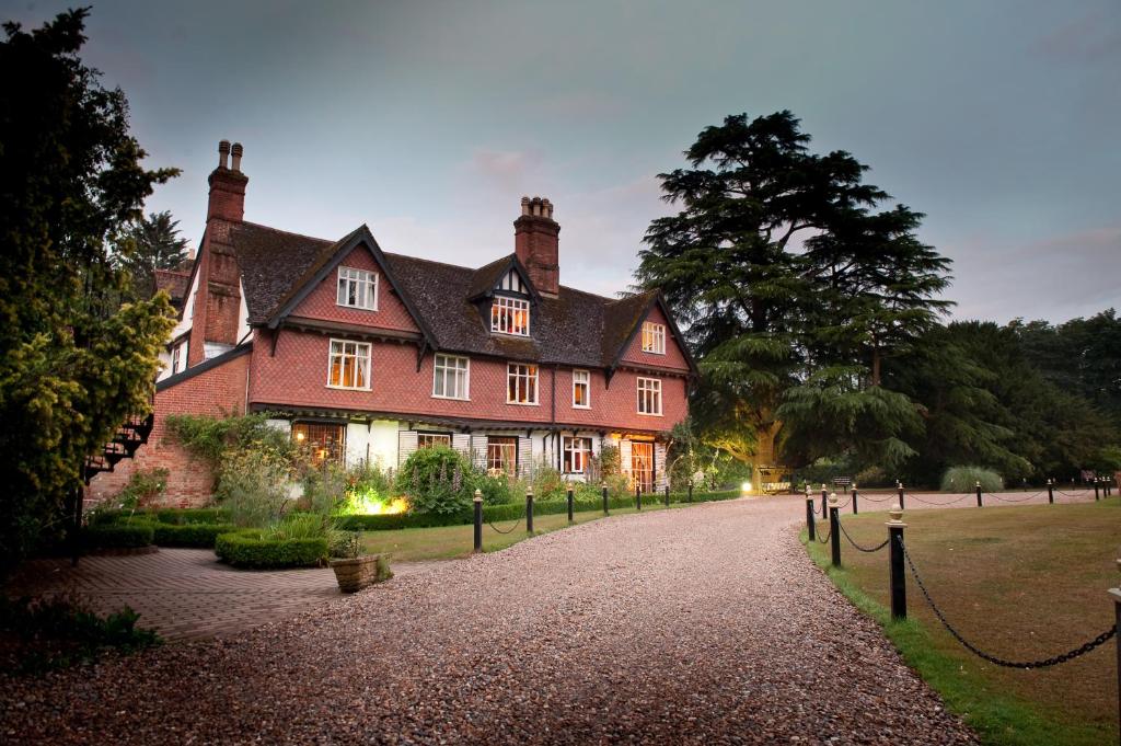 a large red house with a driveway in front of it at Ravenwood Hall Hotel in Bury Saint Edmunds