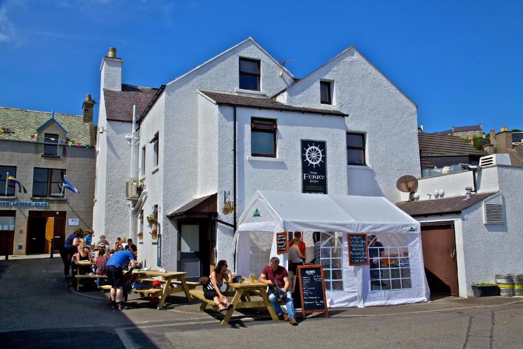 people are gathered around a tent in front of a building at Ferry Inn in Stromness